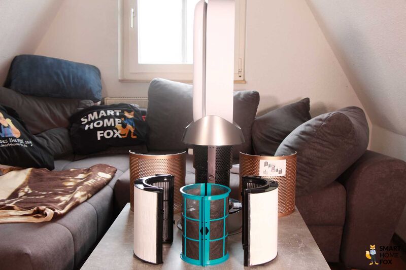 Der Dyson Purifier Hot+Cool Formaldehyde HP09 steht geöffnet auf einem Tisch und der katalytische Filter (Anti-Formaldehyd) und HEPA H13, sowie Aktivkohlefilter stehen daneben.